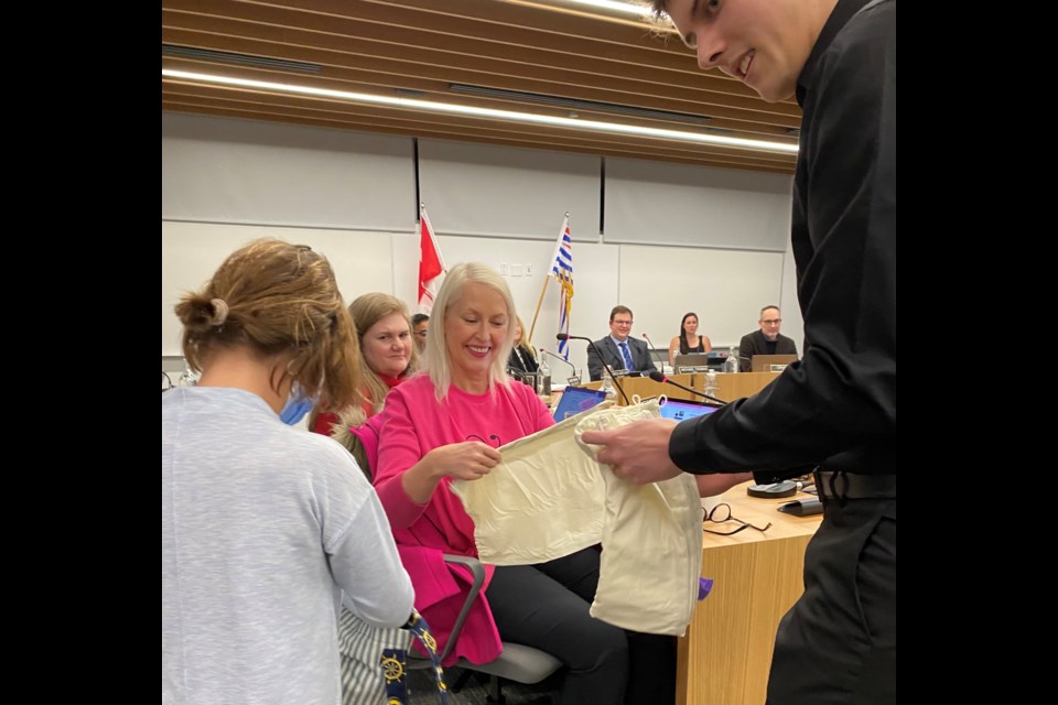 A cloth bag is handed to Port Moody trustee Zoe Royer to bring awareness to RAC (Real Acts of Caring) week Feb. 12-18.