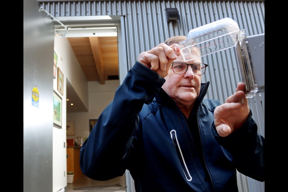 Pat Dennett, a longtime volunteer at the Mossom Creek hatchery in Port Moody, demonstrates an automoatic door opener that's been protected by a cover so a bear can't inadvertantly hit the button and get in.