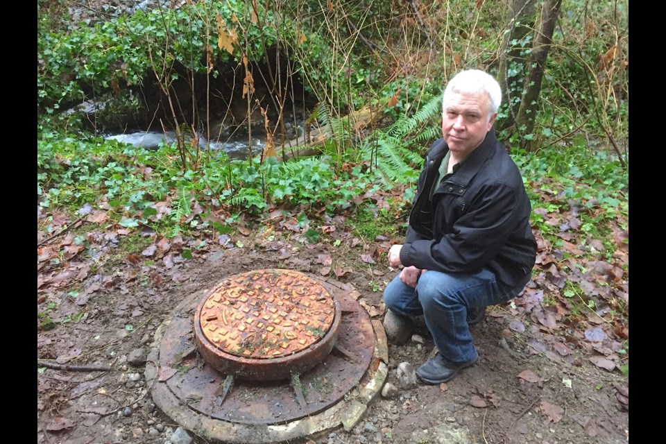 Dave Irving next to the manhole that blew its lid and sent sewer and rain into Stoney Creek (background).