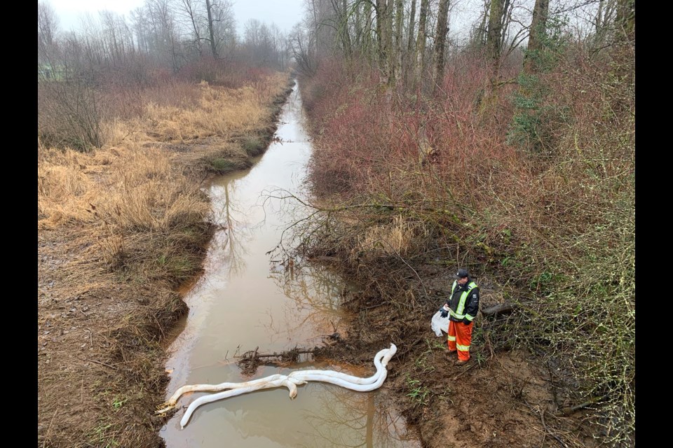 Crews set up a boom to contain a fuel slick in a creek off the Pitt River in Port Coquitlam.