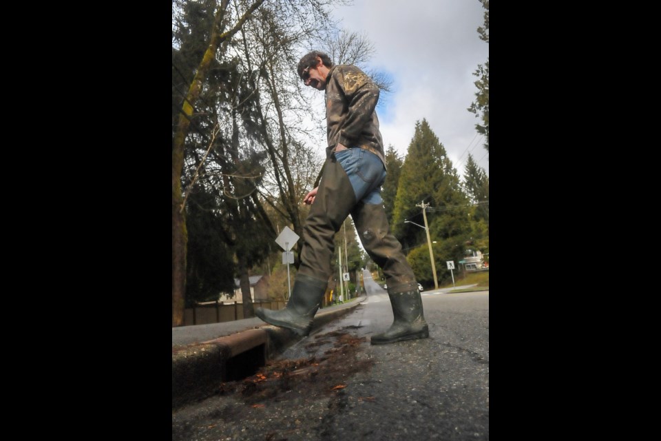 John Templeton, head of the Stoney Creek Environment Committee, steps over a stormwater drain opposite Oakdale Park in Burquitlam. In January 2020, a manhole just a few metres away burst during heavy rainfall, spewing toxic effluent and littering the street with toilet paper. It is one of dozens of such incidents in recent years, a problem compounded by aging infrastructure and heavy rain. 