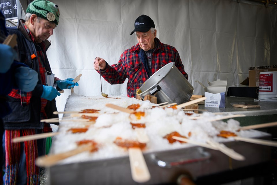 Arcel Girard pours hot maple syrup onto snow to make la tire from la Cabane à Sucre André Beauregard.