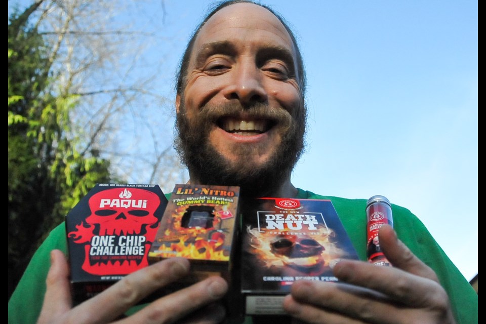 Dave McCloskey displays a menu of spicy edibles, from Paqui's One Chip Challenge and Lil Nitro gummy bear — the "world's spiciest" — to Death Nut and the Tube of Terror. They are all part of a live-streamed challenge aimed at raising money for the Tri-Cities food bank. - Photograph by STEFAN LABBÉ/TRI-CITY NEWS