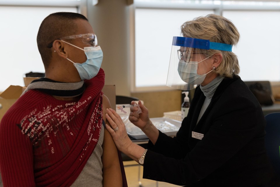A doctor inoculates a СƵ health care worker with the COVID-19 vaccine from Pfizer-BioNTech.