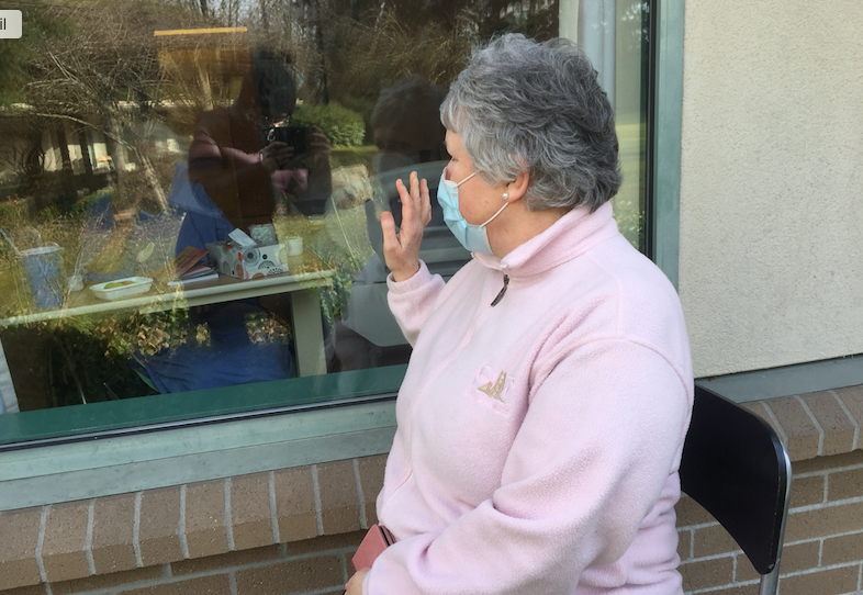 Sue Dupuis waves to her mom who is inside her room at Eagle Ridge Manor. The Port Moody woman worries her mom will go into decline if she can't care for her as an essential visitor.