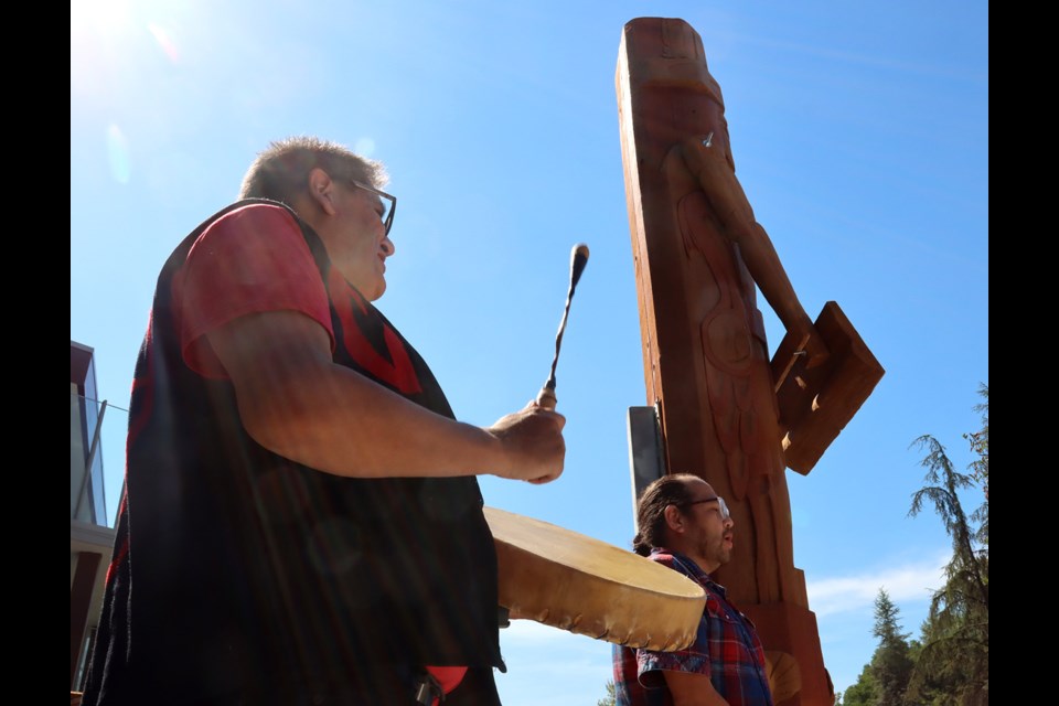 The 600 year-old western cedar log that's been carved into a house post is blessed with traditional Kwikwetlem song.