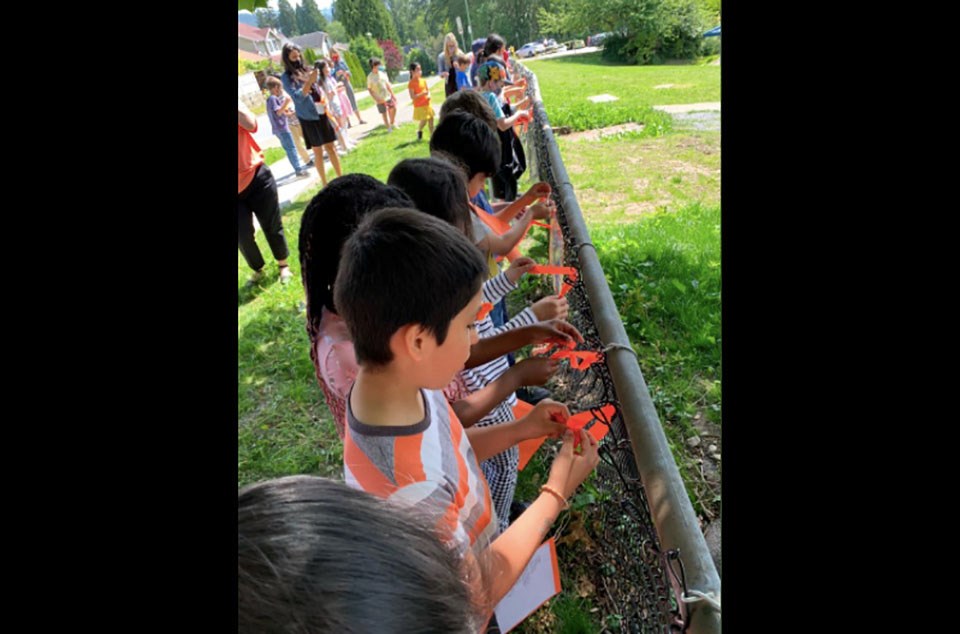 Children tie orange ribbons onto a fence outside Walton Elementary in Coquitlam.