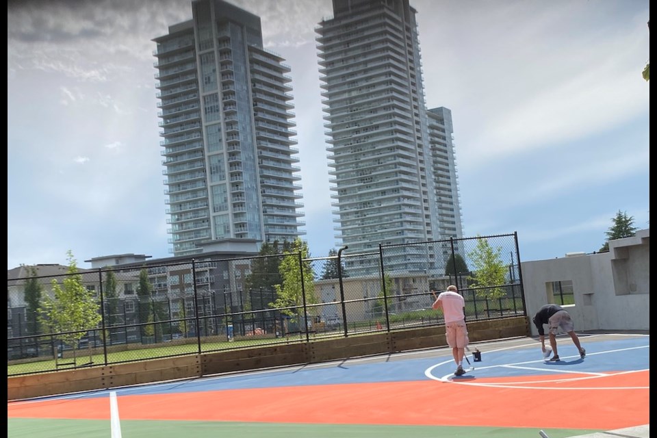 Workers put the finishing touches on a sports court at Cottonwood Park, which was recently expanded to serve the growing neighbourhood of Burquitlam.
