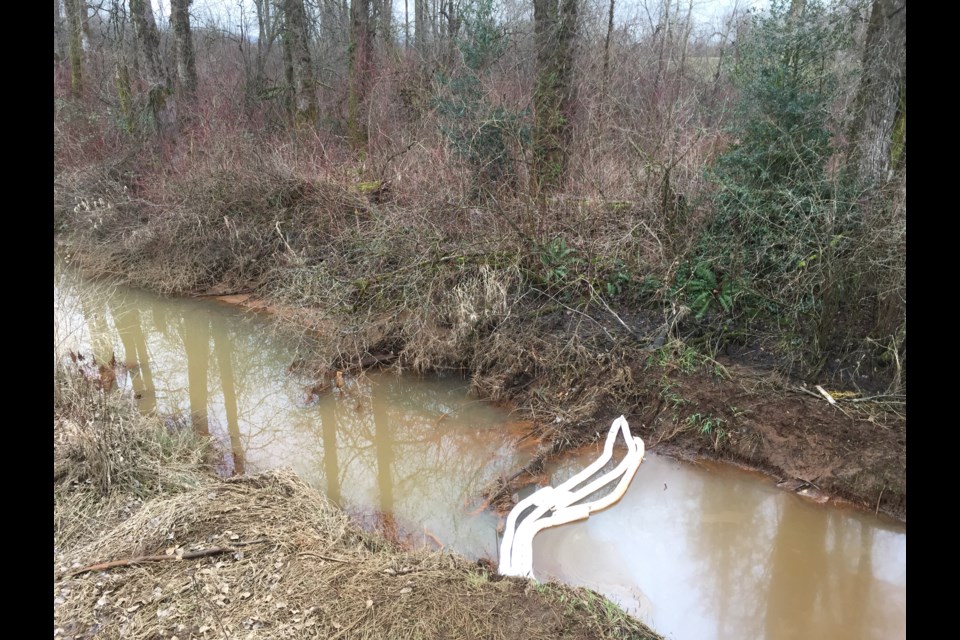 Absorbent booms stop diesel fuel from flowing upstream but there is still a film of diesel fuel on the water.