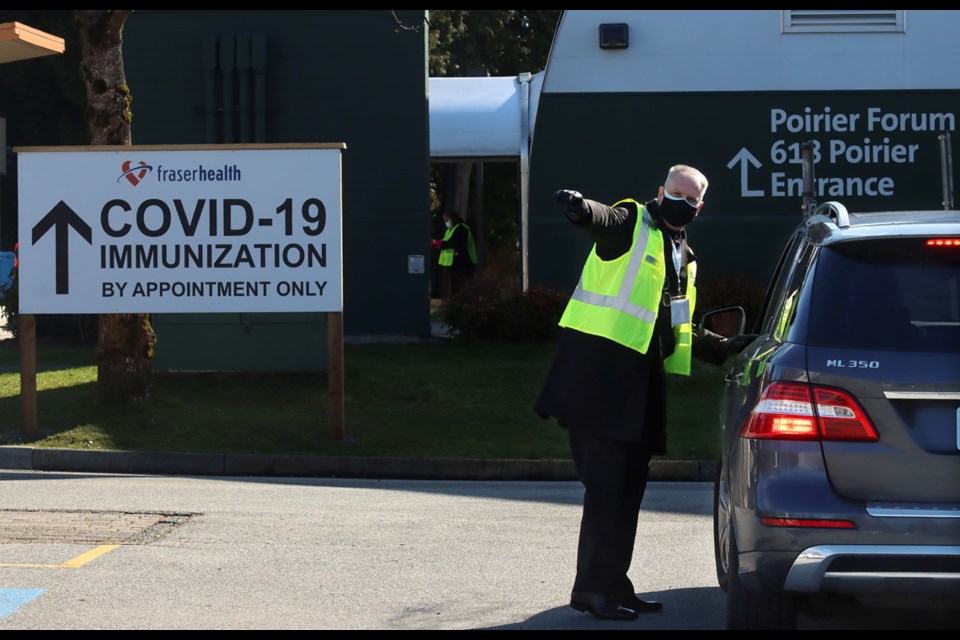 A volunteer provides directions to people arriving at the new COVID-19 mass vaccination clinic that opened Monday at the Poirier Forum in Coquitlam.