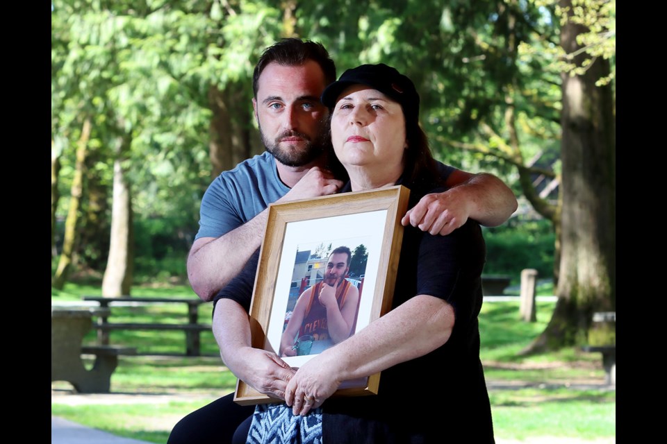 Belinda Ruckman is comforted by her son, Riley, as she holds a photo of her other son, Reno, who died of a drug overdose.