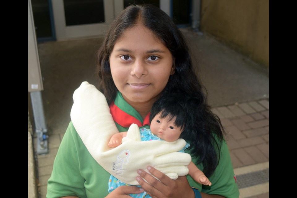 Port Coquitlam's Insiyah Dharsee demonstrates how a Zaky HUG works to comfort premature babies. She's spent more than a year painting rocks to raise funds to purchase 24 pairs of the devices as well as a special waterless bottle warmer for the Neonatal Intensive Care Unit at Royal Columbian Hospital in New Westminster.