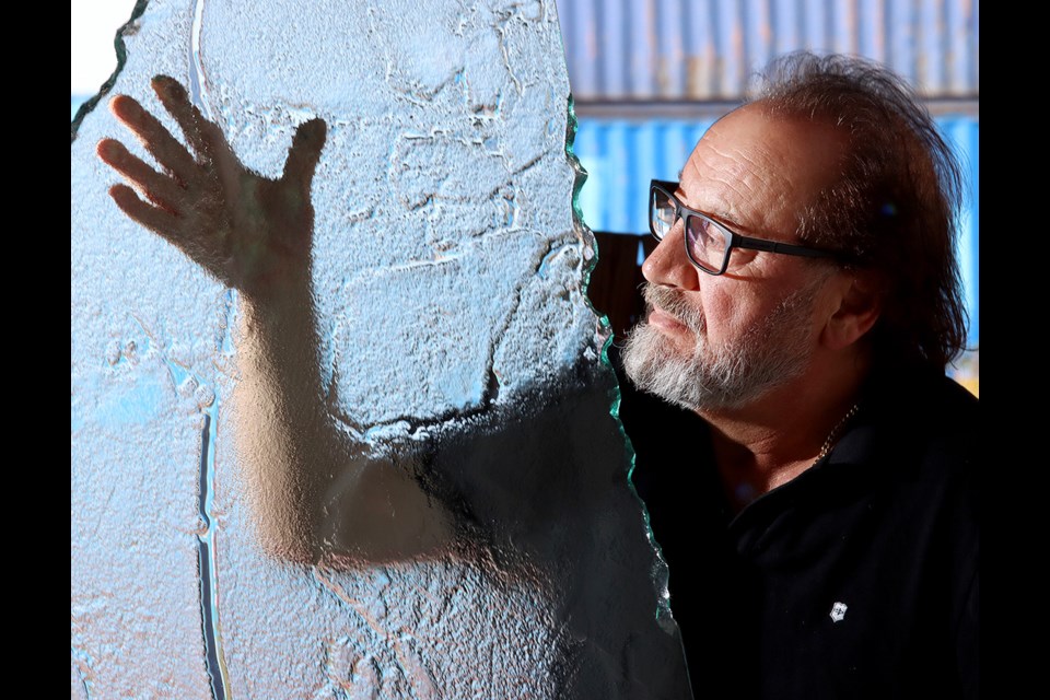 Naser Niki shows off a textured glass panel like the ones he crafted to create the cauldron at Jack Poole Plaza used in the 2010 Winter Olympics in Vancouver. He'll be creating new panels to replace several which were recently damaged by vandals.