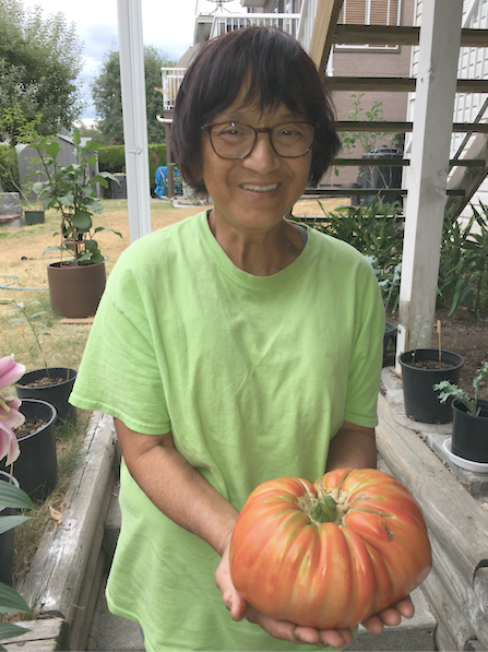 Betty Quon with the giant tomato she grew in her plot in the community garden at Colony Farm Regional Park.