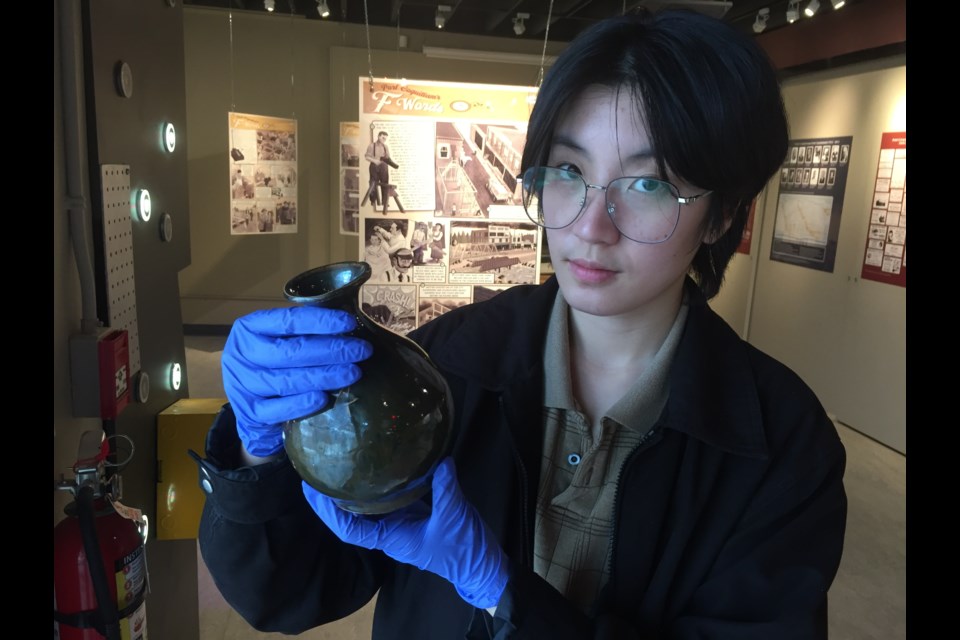 Heritage Woods Secondary student Queena Li with glassware likely used for alcohol. It was stored in the Port Coquitlam archives.