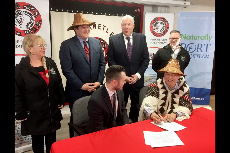 Port Coquitlam Mayor Brad West and Kwikwetlem First Nation chief Ed Hall sign a servicing agreement for a new development while councillors look on.