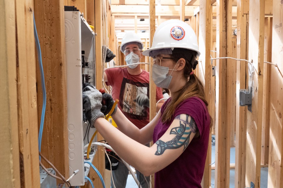 Two students working together on their wiring module in their ‘mock’ condo.