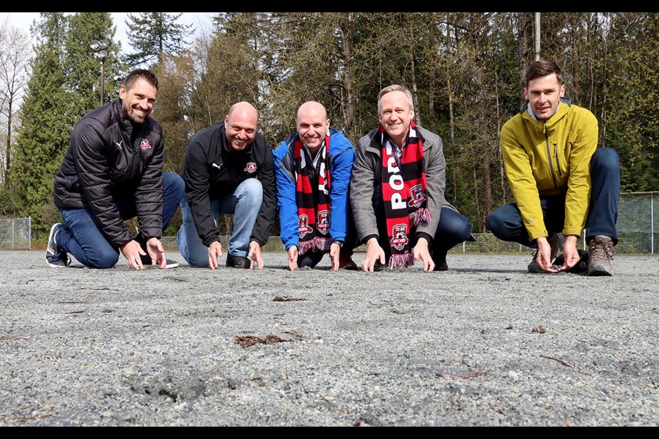 Srdjan Djekanovic, the executive director of Port Moody Soccer Club, and Matthew Campbell, its president, dig into the hard gravel surface at Inlet Field along with provincial Minister of Municipal Affairs Nathan Cullen, Port Moody-Coquitlam MLA Rick Glumac and Mayor Rob Vagramov after an announcement that funding has been secured for a new turf field at the park.