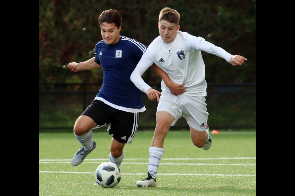 Dr. Charles Best Blue Devils forward Leito Hutchinson and Pinetree Timberwolves defender Joel Badger battle for control of the ball in the first half ot their Coqutlam Secondary Schools Athletic Association senior boys soccer match, last Tuesday at Town Centre Park. Best won the match, 3-2, on goals by Bradley Wong, Luca Di Francesco, and Cole Toupin. Sam Kim and Adam Alomary replied for the Timberwolves.