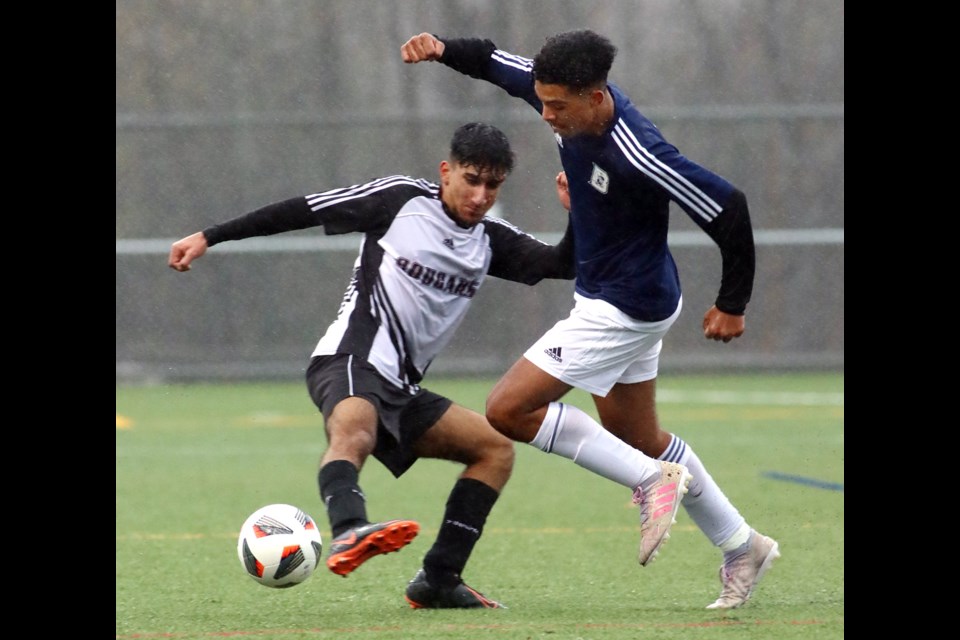 Jalen Harrison, of the Dr. Charles Best Blue Devils, tries to get past an Enver Creek Cougars defender in the first half of their preliminary round match at the boys high school soccer AAA Coastal Provincial championships, Thursday at the Burnaby Lake Sports Complex West. Best won the match, 3-1.