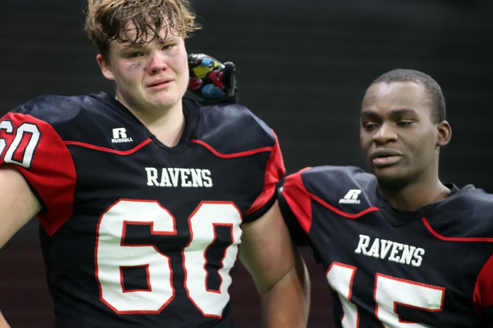 Terry Fox Ravens defensive lineman Kaiden Exner (#60) is consoled by teammate Alex Ndagijimama (#15) after their 36-33 loss to the G.W. Graham Grizzlies in the BC High School AAA Coastal Subway Bowl championship (Dec. 4, 2021) at BC Place.