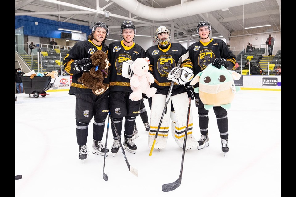 Coquitlam Express players pose with several stuffed animals thrown onto the ice after they scored the first goal of the Teddy Bear Toss affair on Nov. 26, 2021.