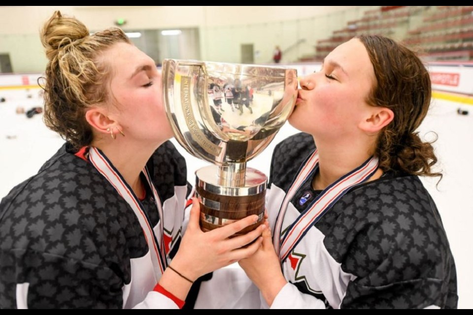 Coquitlam's Jordan Baxter (right) kisses the IIHF under-18 women's world championship trophy after Canada defeated the United States 3-2 in the final on June 13, 2022.