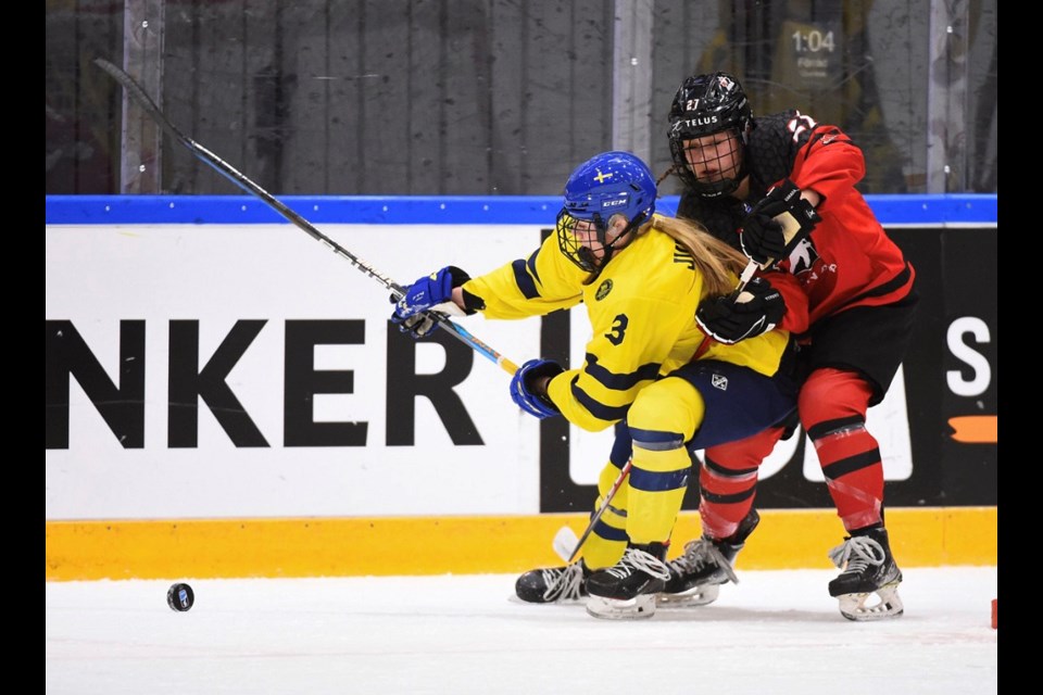 Coquitlam's Jordan Baxter (#27) tries to skate around a Swedish defender to get to the puck during Canada's preliminary match at the 2023 under-18 women's world hockey championships.