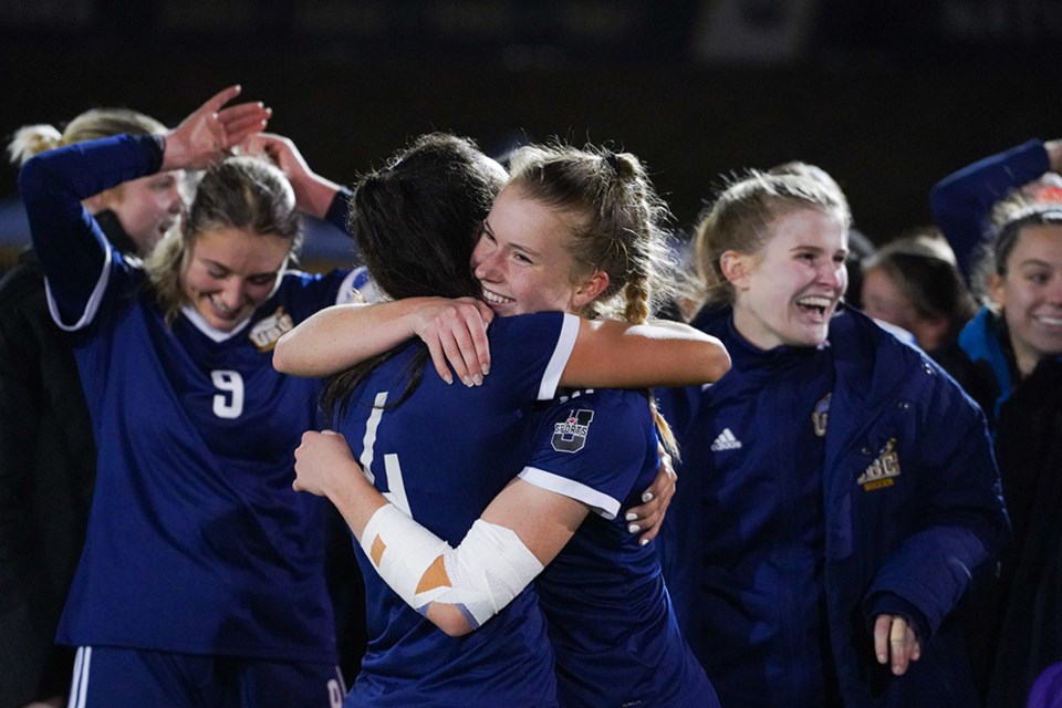 Coquitlam's Sophia Ferreira (#4) embraces her teammate after UBC claimed its 16th Canada West women's soccer championships in school history. She recorded an assist and was named the team's MVP of the gold-medal match.