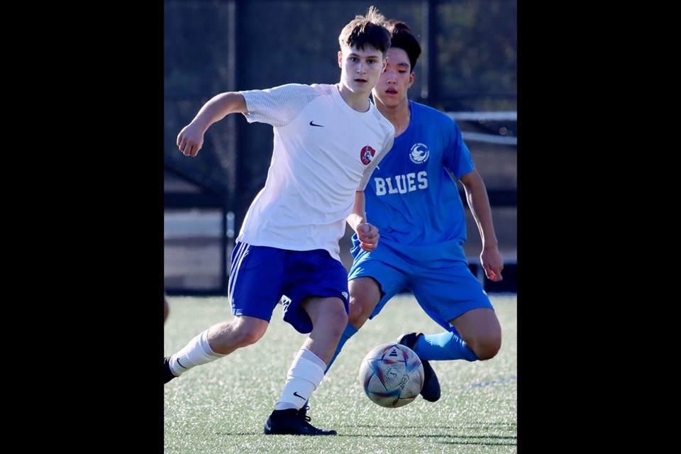 Centennial Centaurs' Nick Matheson shields the ball from a Port Moody Blues defender in the first half of their Coquitlam Secondary Schools Athletic Association senior boys soccer match on Oct. 12, 2023, at the Centennial turf field. Matheson scored the winning goal in the Centaurs' 3-1 victory.