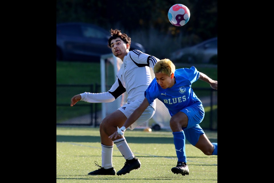 Dr. Charles Best forward Manas Lalsinghani battles a Port Moody Blues defender for controlof the ball in the first half of their Coquitlam Secondary Schools Athletic Association senior boys soccer match, Thursday at Dr. Charles Secondary School. The Blue Devils won 2-0.