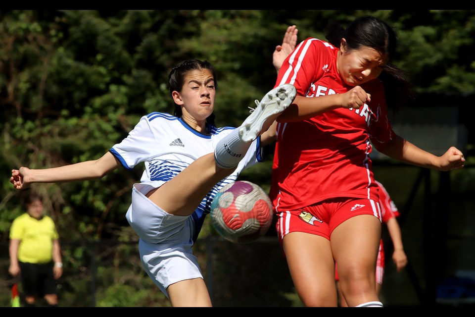 Melina Gunther (left) of the Dr. Charles Best Blue Devils stretches to get a shot past Burnaby Central Wildcats defender Kaitlynn Siu in the first half of their Fraser North Zone semifinal match at Dr. Charles Best Secondary School on May 9, 2024.