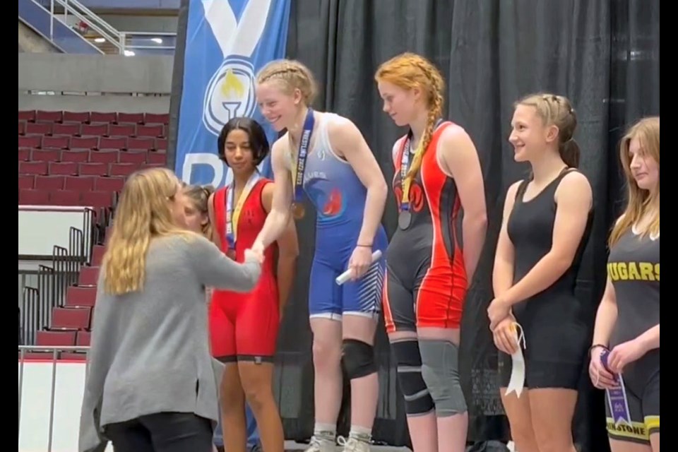 Port Moody's Ella Finding (middle) is all smiles while receiving her second straight B.C. high school wrestling provincials gold in the female 57 kg category.