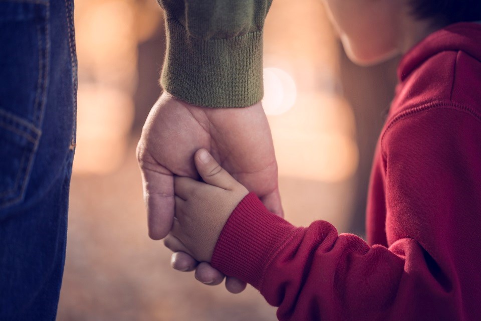 Man holding child's hand - Getty Images