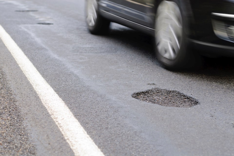 getty-image-pothole-with-a-car-driving-past