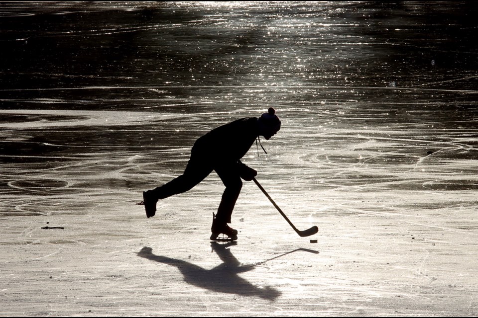 A shinny player chases down the puck on frozen Como Lake on Sunday.