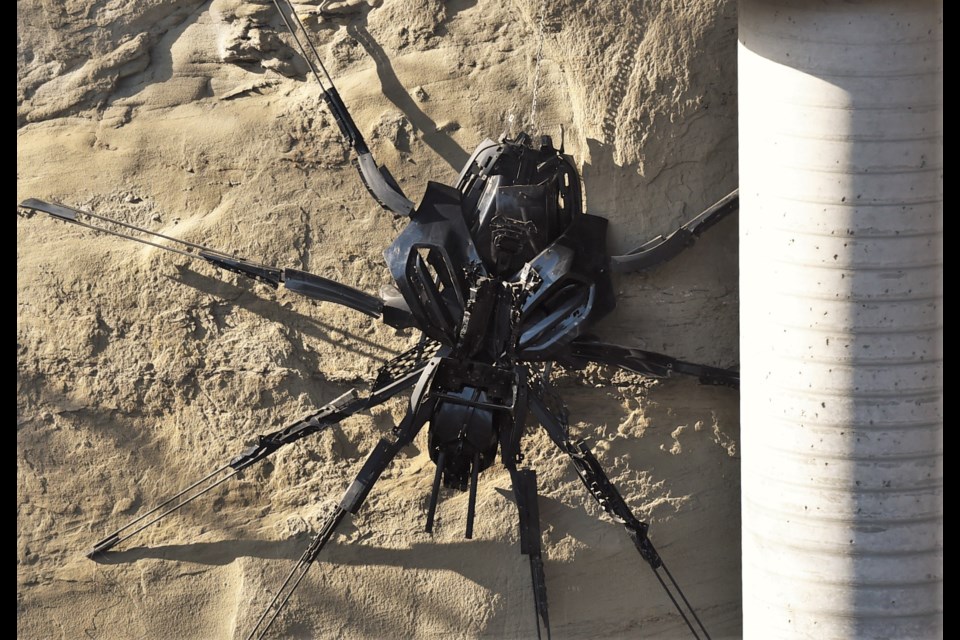 The piece uses large pieces of plastic to create a spider-like form.