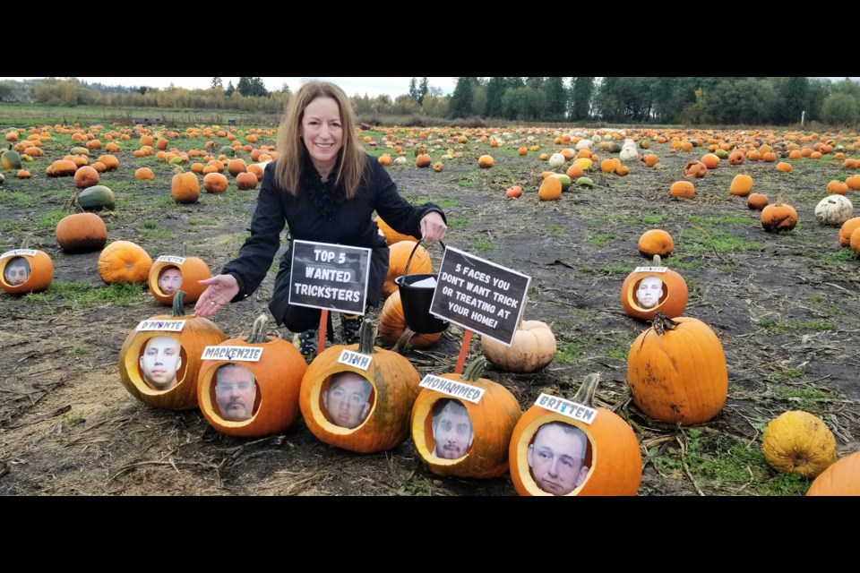 Linda Annis, executive director of Metro Vancouver Crime Stoppers, in a pumpkin patch with photos of the five wanted men in pumpkins.
