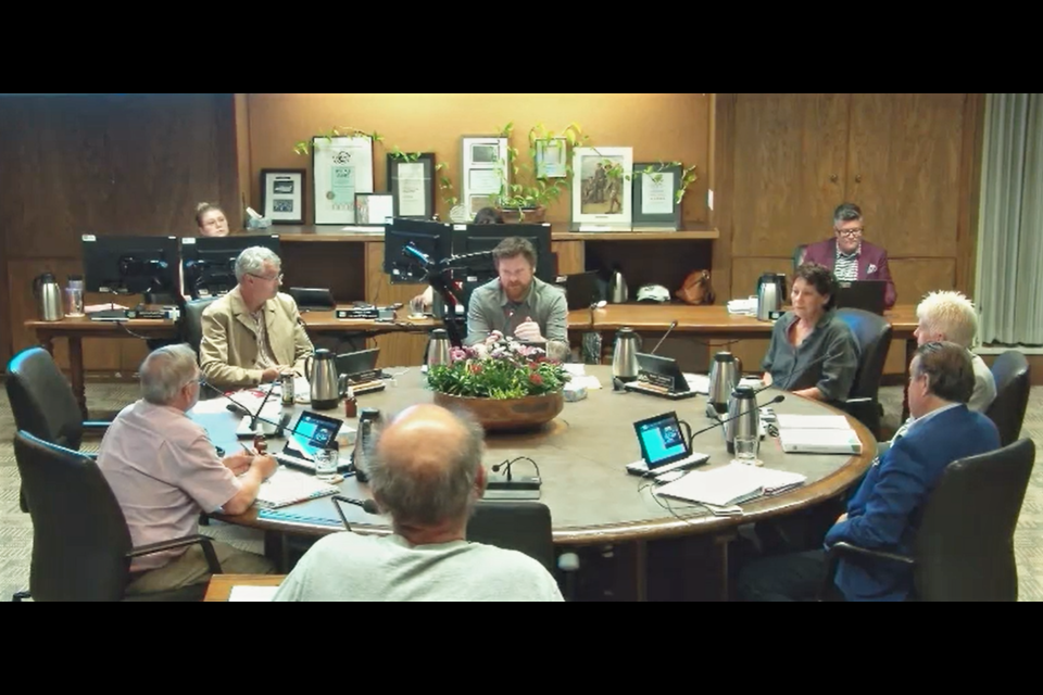 In the video of the meeting, committee chair Camil Dumont (centre, seated facing camera) speaks with member of the public Phil Rankin (centre, standing, facing away from camera).