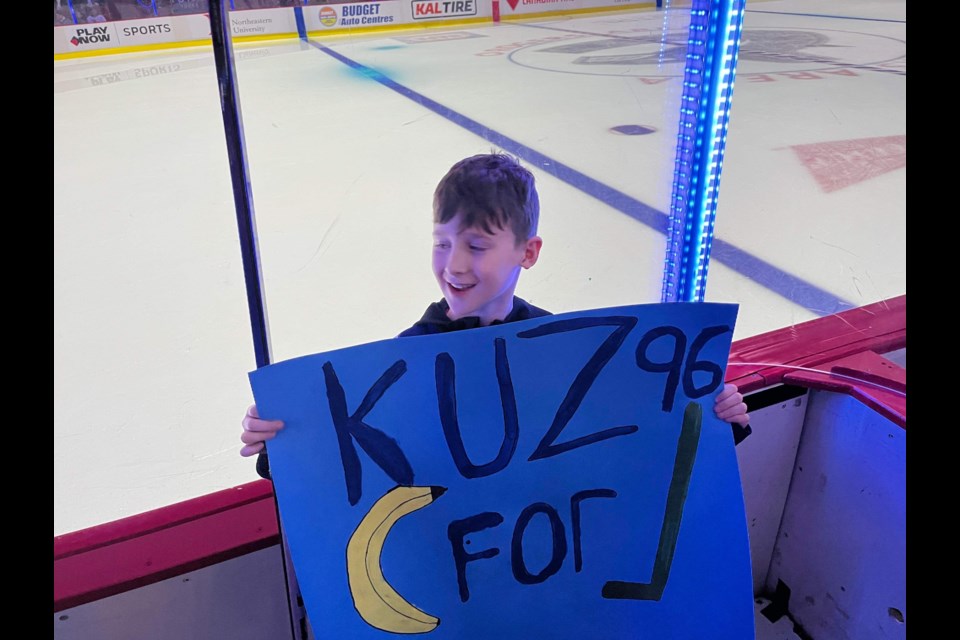 Oliver with his sign asking to trade a banana to Andrei Kuzmenko for a hockey stick.