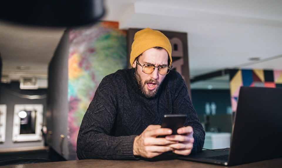 man-shocked-looking-at-phone-sextortion-in-vancouver