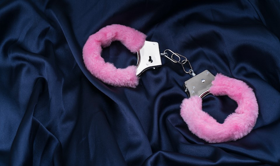 pink-fuzzy-handcuffs-on-blue-silk-sheets