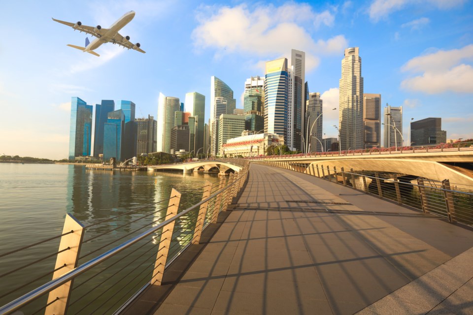 Airplane flying over Singapore city in the morning.