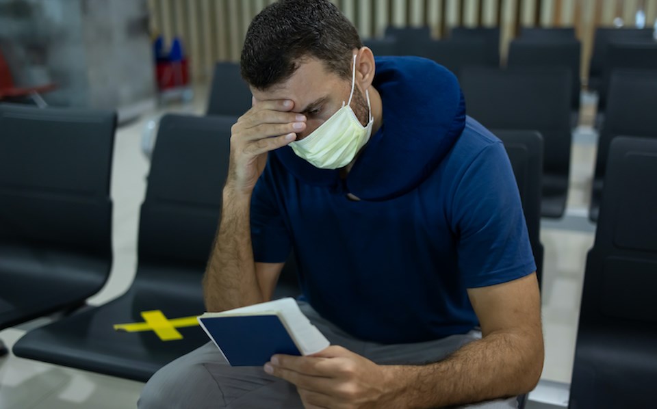 man-looks-stressed-out-passport-face-mask-airport