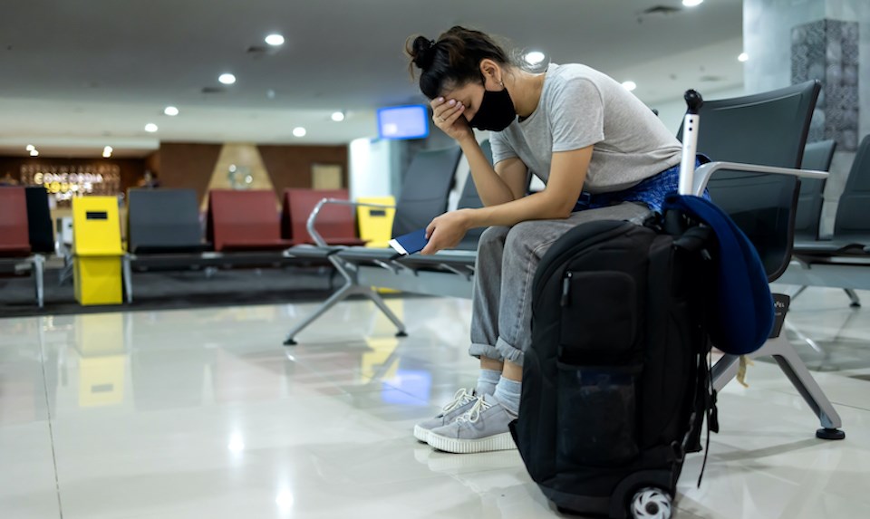 woman-upset-airport-suitcase-face-mask