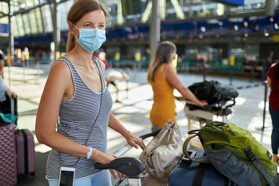 woman-pushing-luggage-airport-wearing-mask-travel