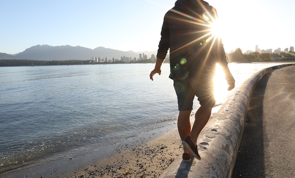 man-walking-vancouver-seawall-sun