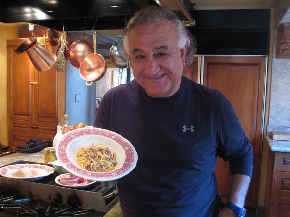  Umberto Menghi holding the Spaghettini Carbonara he just cooked for producer Elaine Chau in his kitchen at home. Photo courtesy CBC
