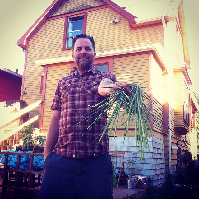  Geoff Huffman with homegrown goods in the backyard of Katy and Geoff Huffmans' heritage house in Hastings Sunrise. They have been planting trees and landscaping inspired by old photos of what was once on the site. They managed to get some grapevine cuttings in the neighbourhood to revive grape growing  that once took place. Photo credit: Huffmans. 