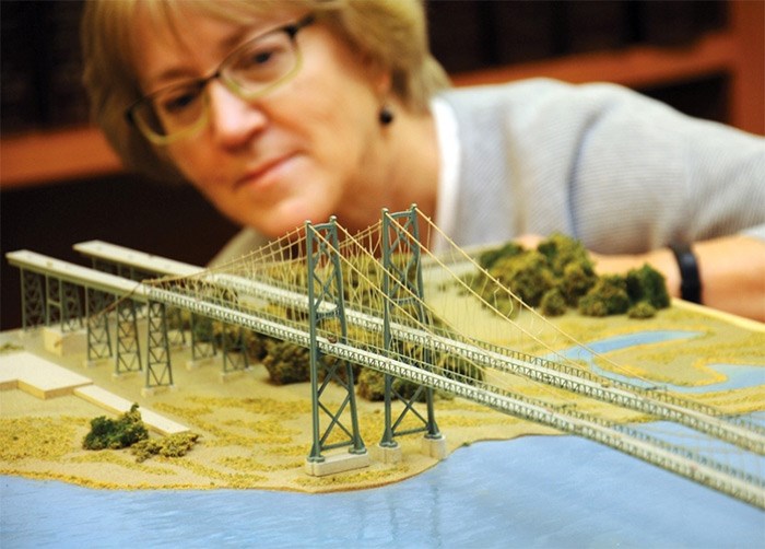  North Vancouver Museum and Archives director Nancy Kirkpatrick examines a model from the 1990s of a proposed twinned version of the Lions Gate Bridge. photo Cindy Goodman, North Shore News